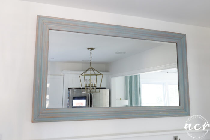 blueish wood framed mirror on wall