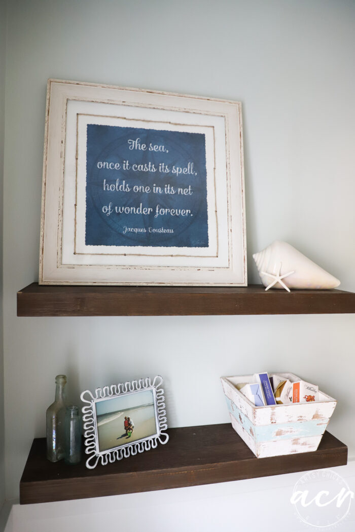 the sea quote in blue with white frame on shelf with other decor
