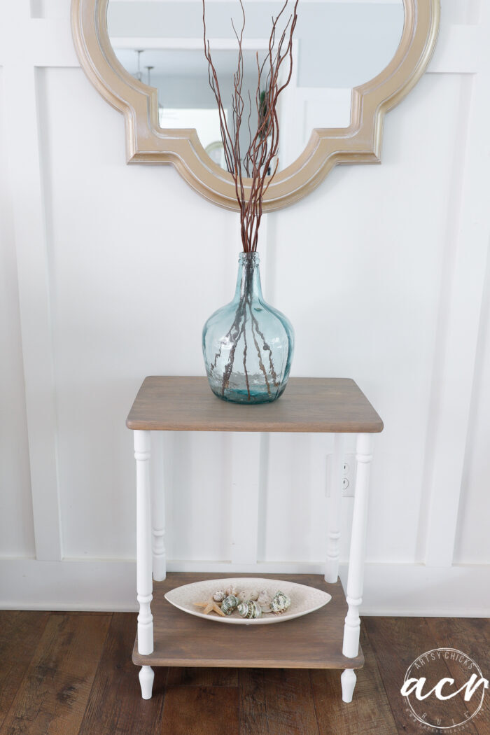 driftwood and white table with blue vase and dish with seashells on bottom