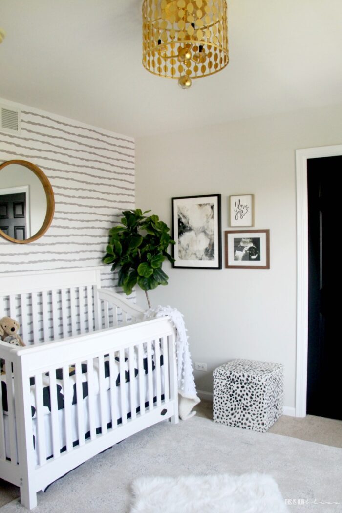 gray and white striped wallpaper accent wall with white crib