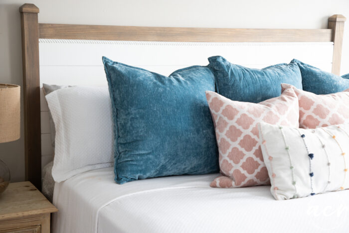 headboard on wall with bedding blue pillows, pink pillows