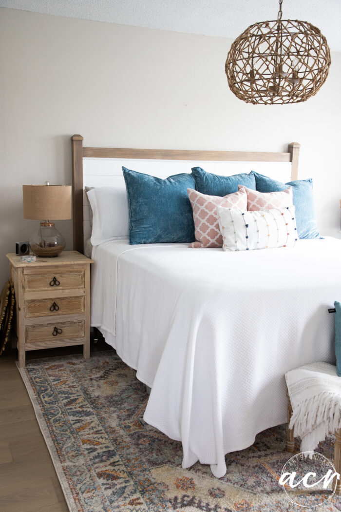 white bed with blue pillows and colorful rug