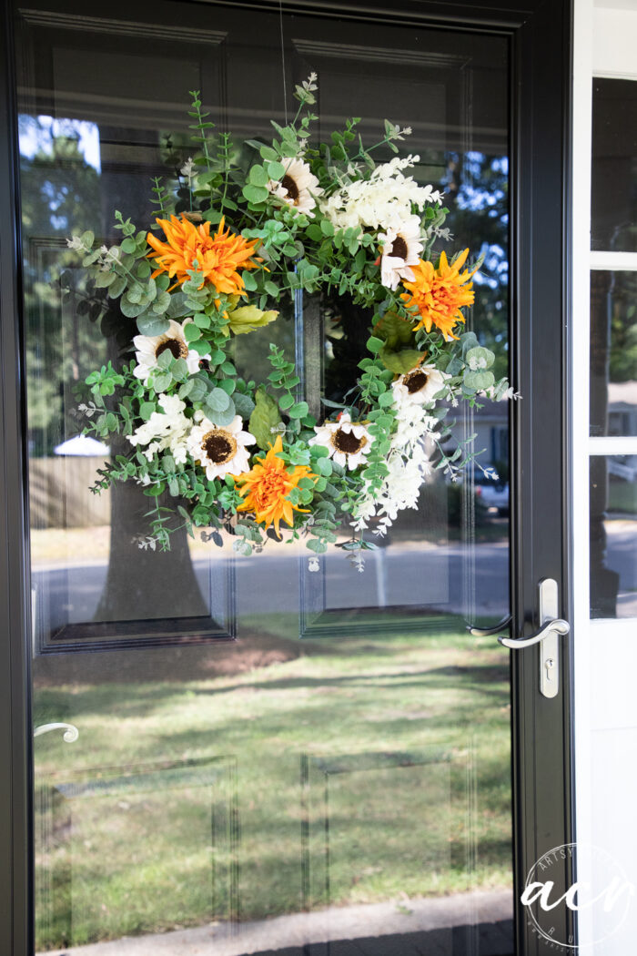 green wreath with white sunflowers and orange flowers on front door