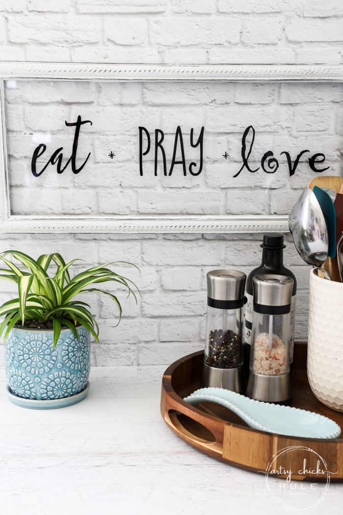 eat pray love glass sign with white frame and plant with wood kitchen tray