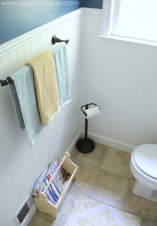 white beadboard wall with blue and yellow towels and white register