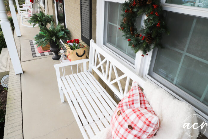 white bench with white throw and red plaid pillow