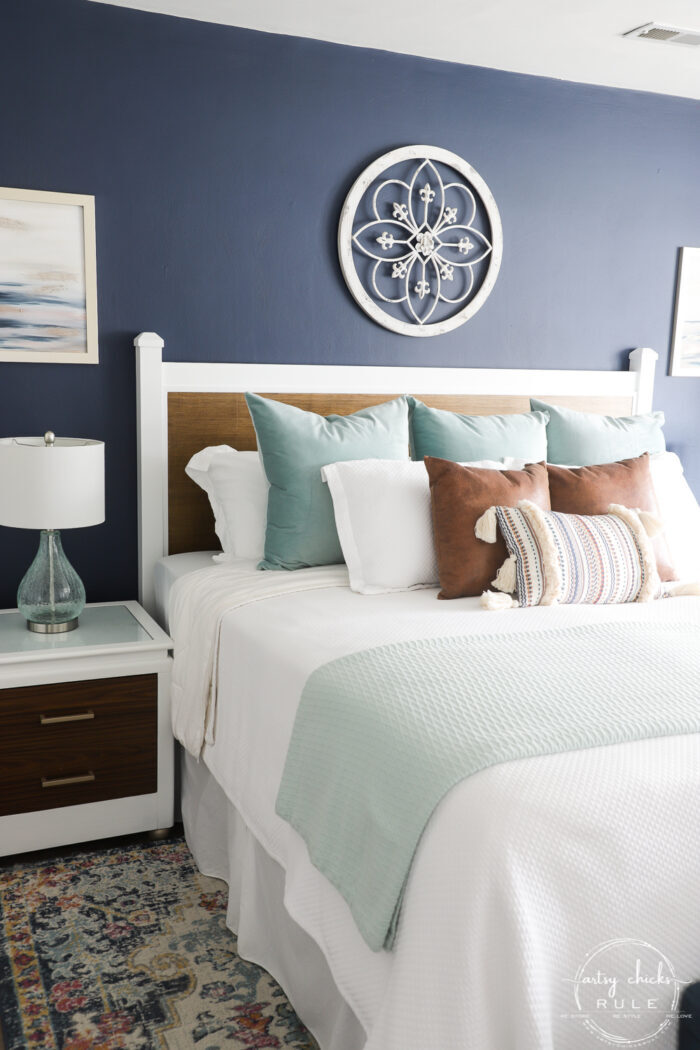 Navy wall, bed with pillows, colorful rug