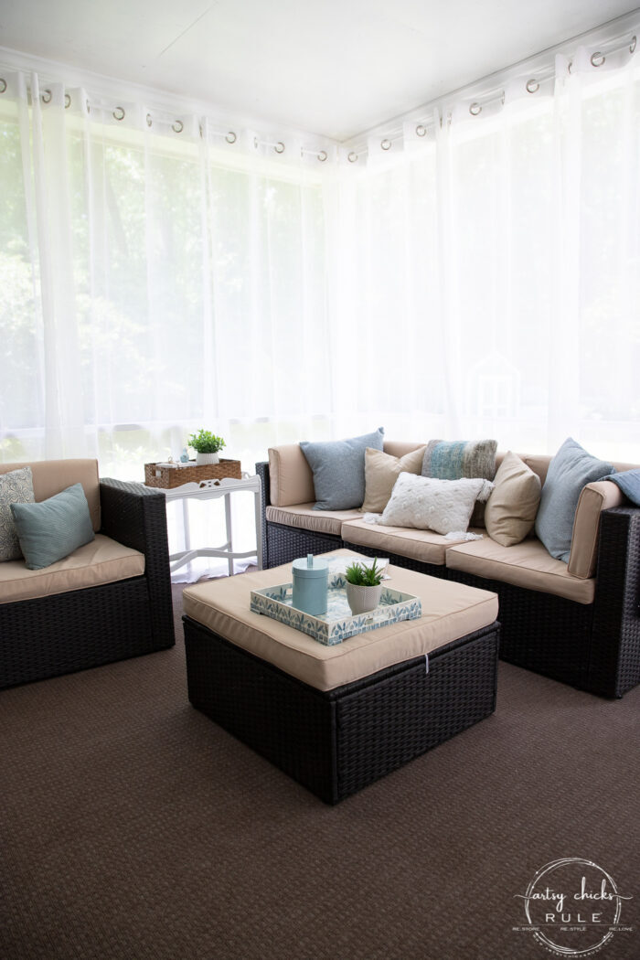 patio furniture with sheer white curtains behind