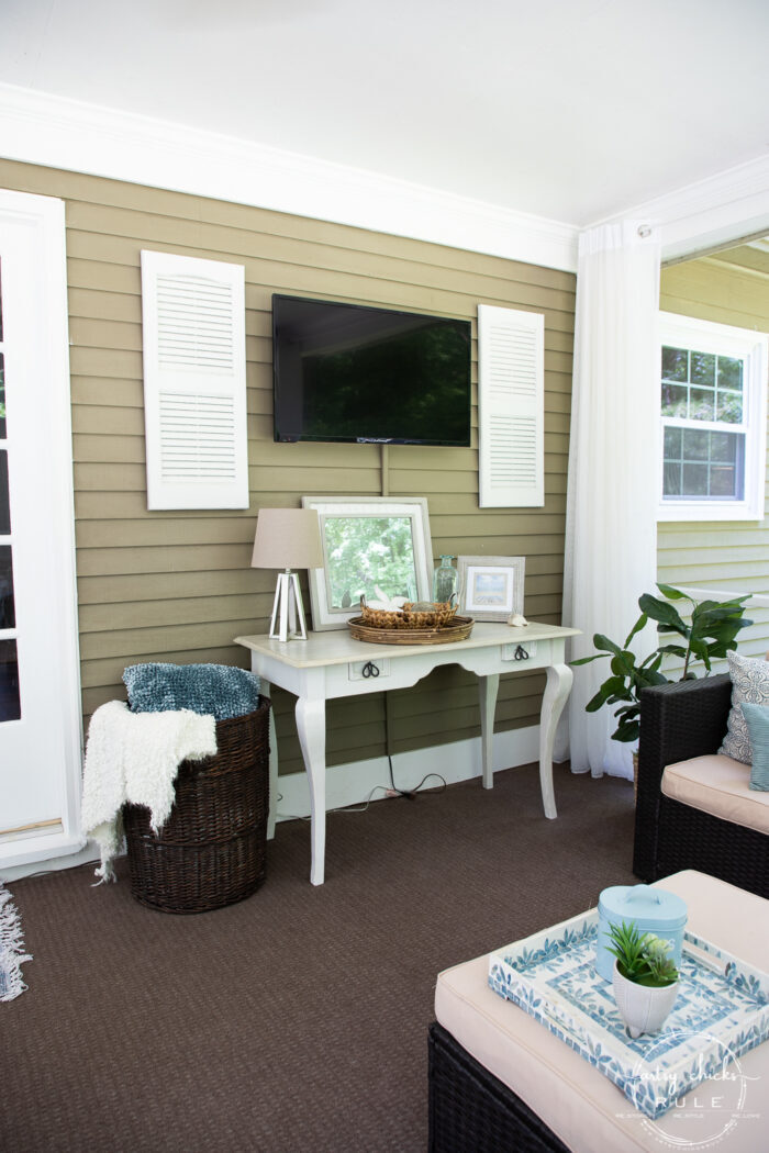 screened porch wall with tv and console table with white shutters