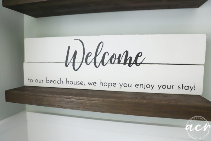 white welcome sign on wood shelf
