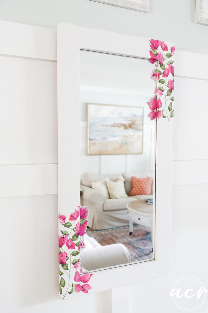 white wood frame mirror with pink flowers on corners on wall